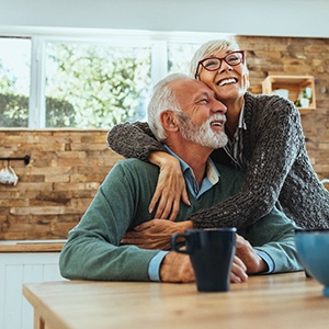 Senior couple smiling and hugging in kitchen