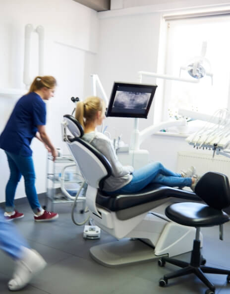 Dental team member walking up to patient sitting in dental chair