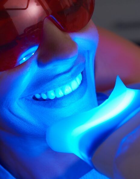 Woman getting professional teeth whitening in dental office