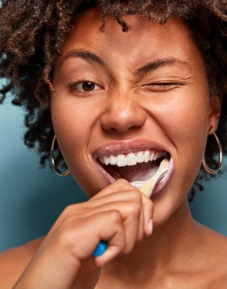 Woman smiling while brushing her teeth