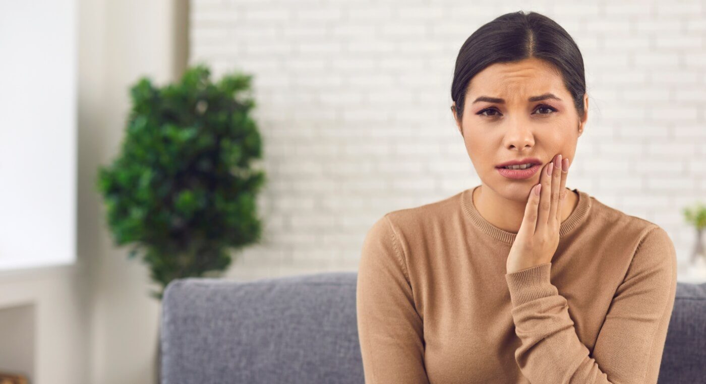 Woman holding her cheek in pain before tooth extractions in Arlington