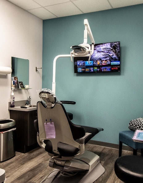 Dental treatment room with television on wall