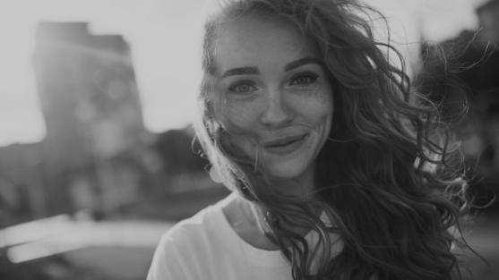 Woman smiling outdoors with her hair blowing in the wind