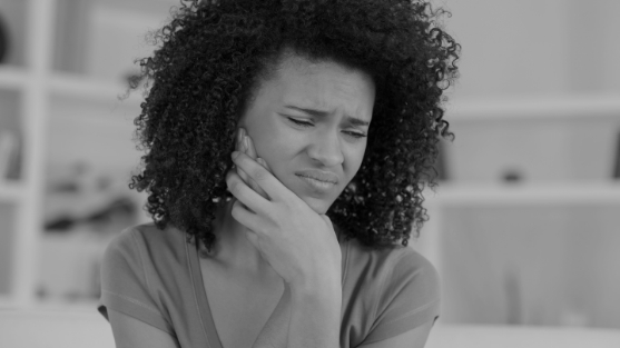 Woman touching her cheek and wincing in pain