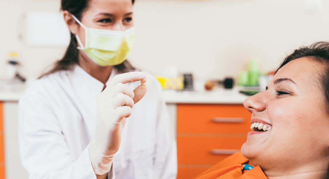 Dentist showing a patient their tooth after wisdom tooth extractions in Arlington