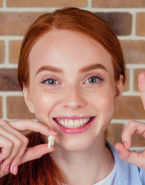 Smiling woman holding her extracted tooth