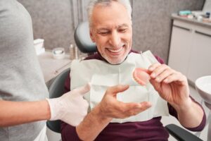 Man handing his dentures to his dentist during his checkup